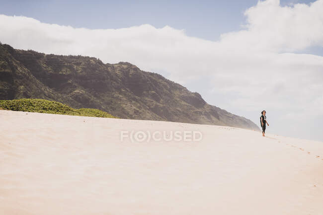 Woman stands on a sandy hill in front of a mountain — Stock Photo