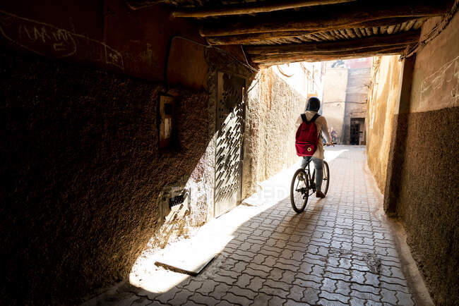 Bicicletas hombre a través de paso subterráneo en Marrakech, Marruecos - foto de stock