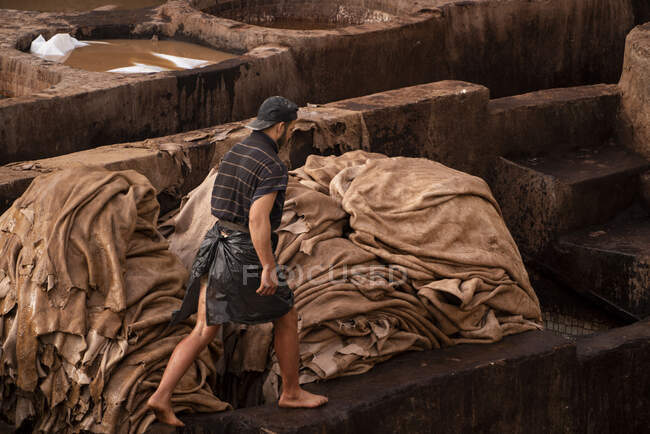Hombre trabajando en curtiduría de cuero en fez, Marruecos - foto de stock
