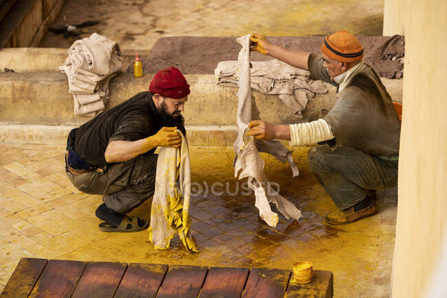Men working with yellow dye and animal hides in fez tannery, Morocco — Stock Photo