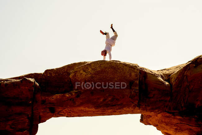 Ein Beduinenmann macht einen Handstand auf einem Felsbogen im jordanischen Wadi Rum — Stockfoto