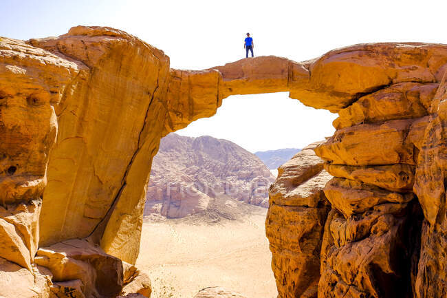 Un uomo si erge su un ponte roccioso nel deserto di Wadi Rum, Giordania — Foto stock