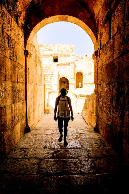 Woman walks under an arch in the ancient Roman city of Jerash, Jordan — Stock Photo