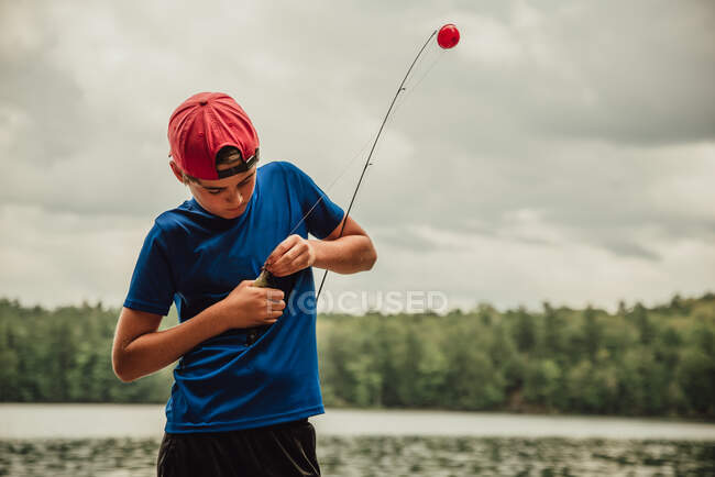 Close up of teen boy with a fish on his rod on a lake in the summer. — Stock Photo
