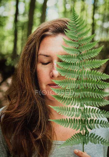 Retrato de mulher com olhos fechados cobrindo rosto com folha de samambaia. — Fotografia de Stock