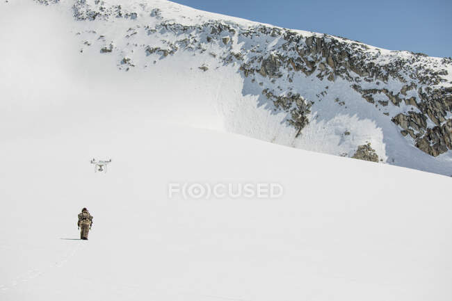 Беспилотник снимает на видео человека Первых наций, идущего по снегу. — стоковое фото