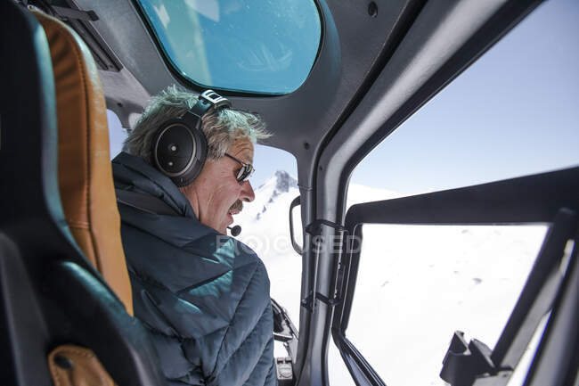 Pilote d'hélicoptère cherche un endroit pour atterrir dans les montagnes enneigées. — Photo de stock