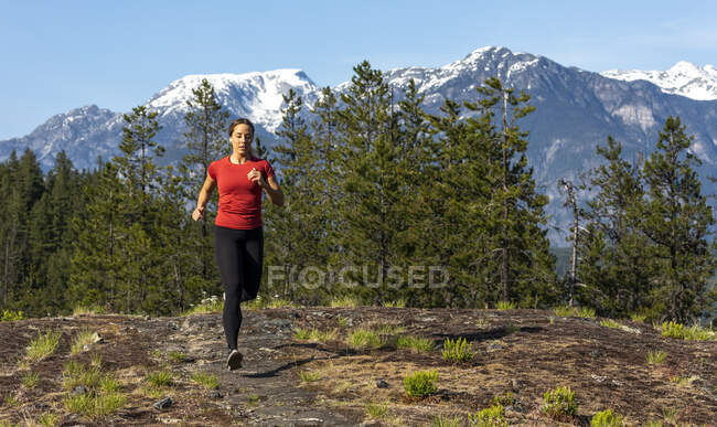 Atleta feminina correndo perto de montanhas — Fotografia de Stock
