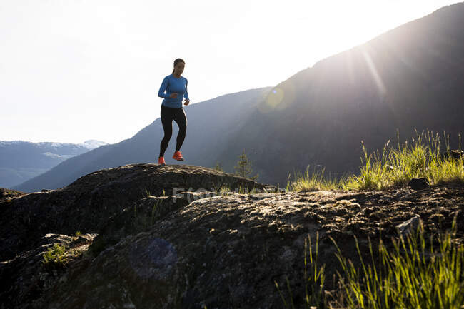 Sportswoman running on stones in highlands — Stock Photo