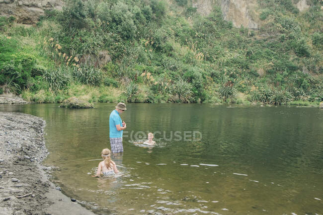 Семья в живописном месте реки играет в воде — стоковое фото