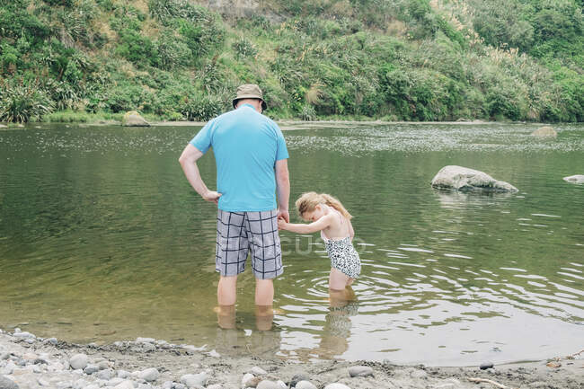 Padre e hija en un pintoresco lugar del río jugando en el agua - foto de stock