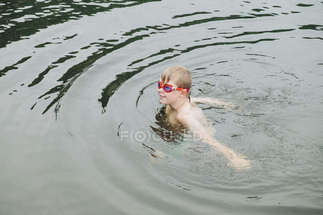 Niño vistiendo googles en el agua - foto de stock