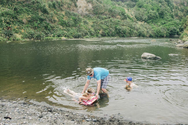 Famiglia in un punto panoramico del fiume che gioca in acqua — Foto stock
