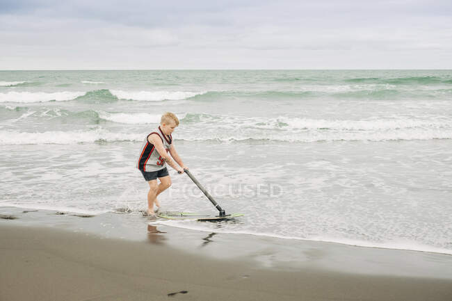 Giovane ragazzo che gioca sulla spiaggia con il suo skim board — Foto stock