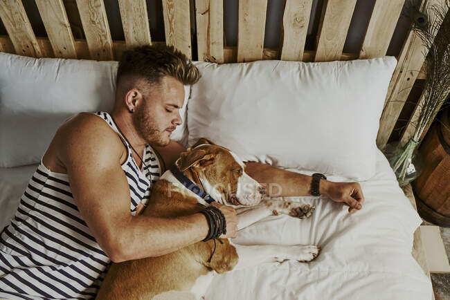 Ein kleiner blonder Junge schläft neben seinem Hund im Bett. Lifestyle-Konzept — Stockfoto