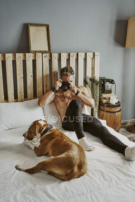 Молодой блондин фотографирует свою собаку в постели. Концепция образа жизни — стоковое фото