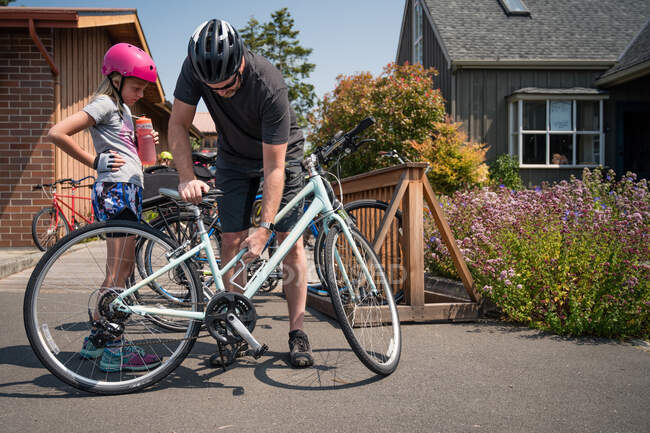 Padre e figlia che indossano i caschi da bici che si preparano ad andare in bicicletta — Foto stock