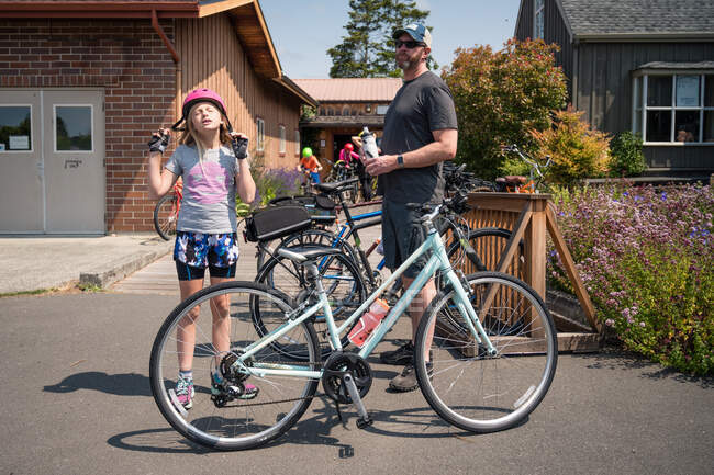 Frustriertes junges Mädchen setzt rosa Fahrradhelm auf Parkplatz auf — Stockfoto