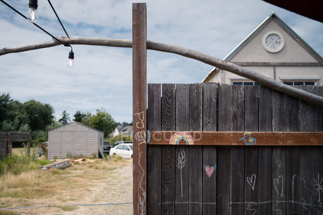 Rustikaler Zaun mit Kreidezeichnungen mit Outdoor-Strukturen und Baumaterialien im Hintergrund — Stockfoto