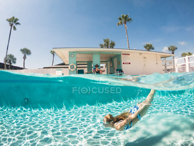 Split Level Punto di vista della ragazza che nuota sott'acqua in piscina in Florida — Foto stock