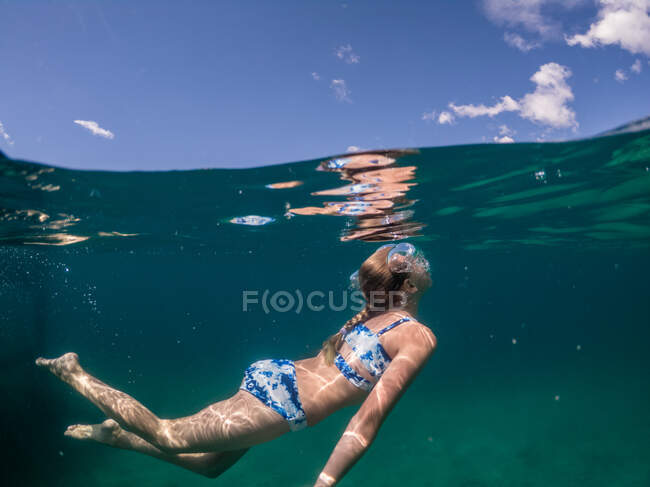 Vista de nivel dividido de la joven nadando bajo el agua en el lago debajo del cielo - foto de stock