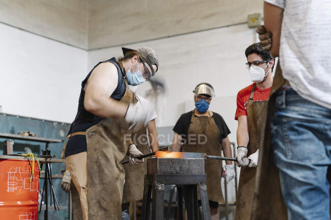 Erntehelfer schmieden Metall in Werkstatt — Stockfoto