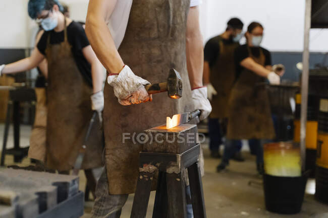 Crop blacksmiths hitting hot metal detail with hammer while forging — Stock Photo