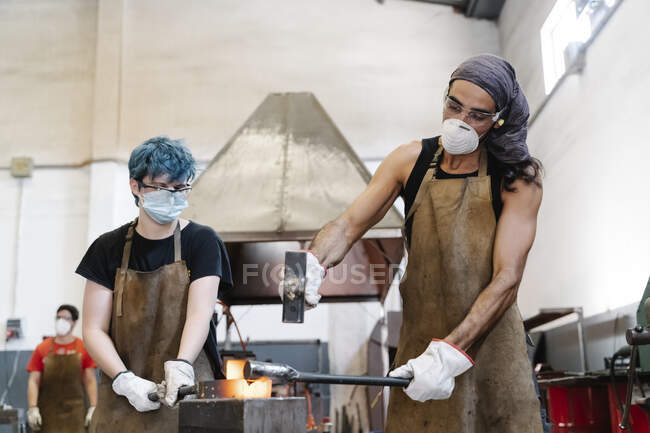 Работники мужского пола ковали железо в мастерской — стоковое фото