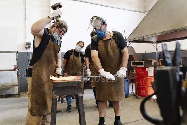 Men in uniform forging metal — Stock Photo