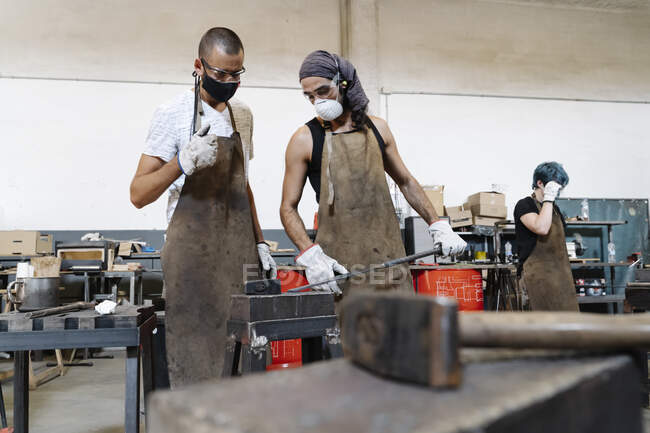 Des hommes sérieux dans des tabliers en atelier — Photo de stock