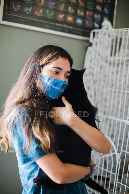 Menina com máscara segurando gato — Fotografia de Stock