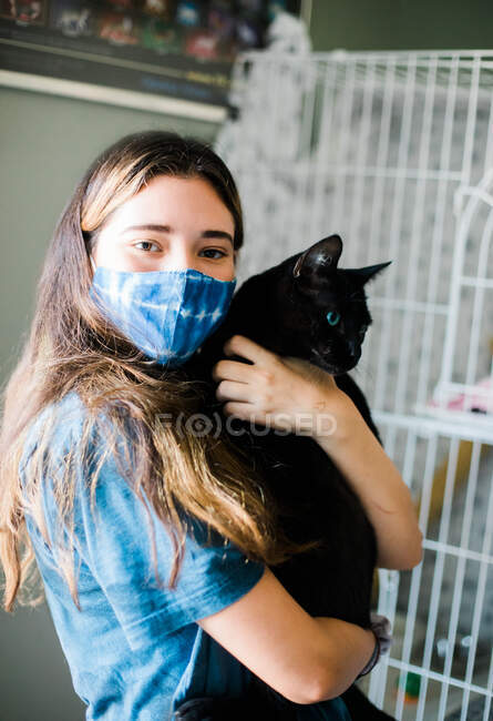 Menina com máscara segurando gato — Fotografia de Stock
