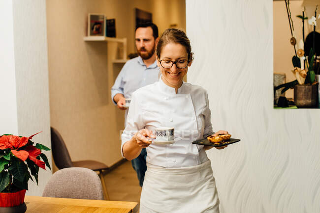 Сотрудники ресторана приносят кофе и десерт к столам — стоковое фото