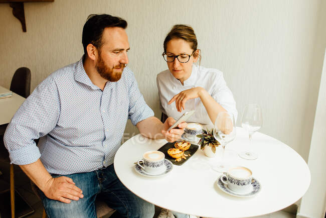 Glückliches Paar beim Frühstück mit pasteis de nata (traditionelle portugiesische Puddingtorte) und Kaffee in einem Café. — Stockfoto