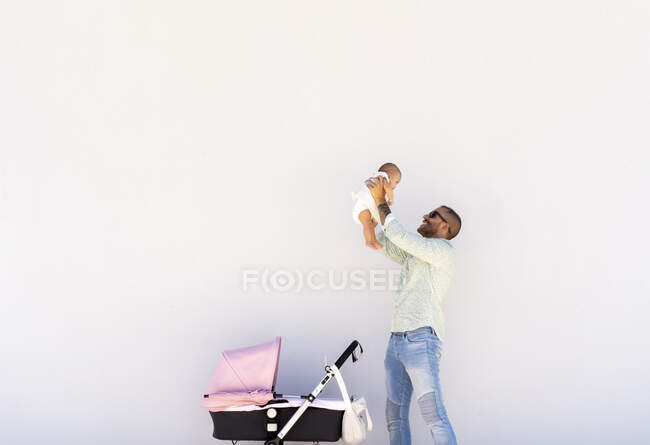 Joven padre amorosamente levantando a su pequeño bebé - foto de stock
