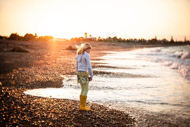 Adolescente em uma praia rochosa na Nova Zelândia ao pôr do sol — Fotografia de Stock