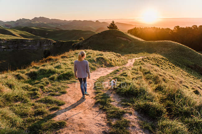 Pre-teen girl walking a dog at sunset on Te Mata Peak in New Zealand — Stock Photo