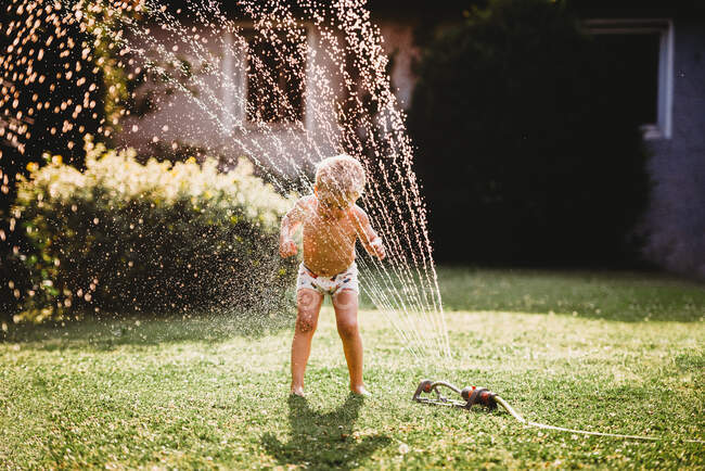 Маленький мальчик играет в саду с водой — стоковое фото