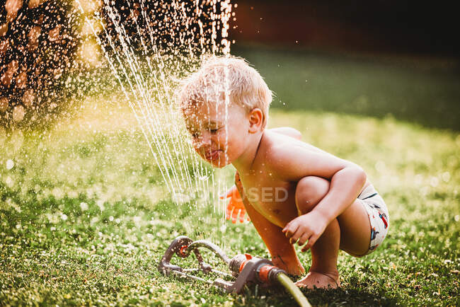 Маленький хлопчик грає в саду з водою — стокове фото