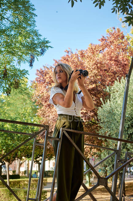 Молода жінка - фотограф тримає в парку камеру. — стокове фото