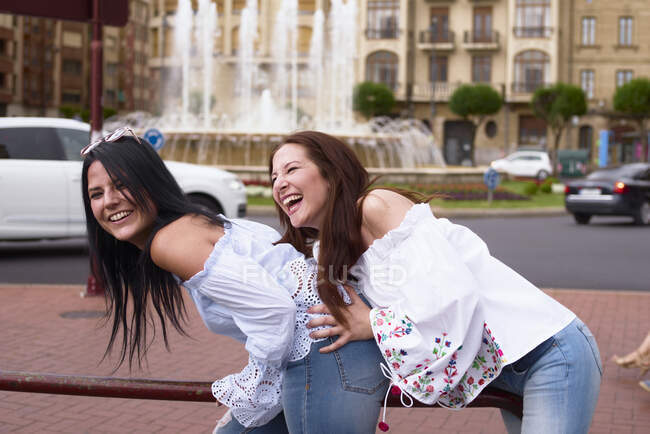Two friends are playing and having fun on a city street — Stock Photo