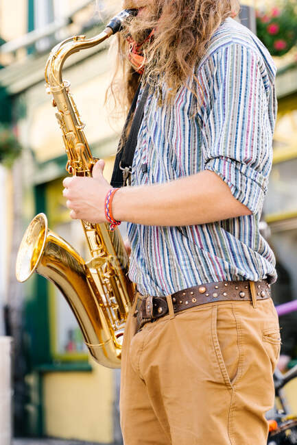 Vertical photo of the hands of a young man with long hair playing saxophone in the street in Galway — Stock Photo