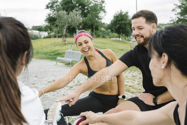 Группа счастливых людей растягивается на открытом воздухе после тренировки — стоковое фото