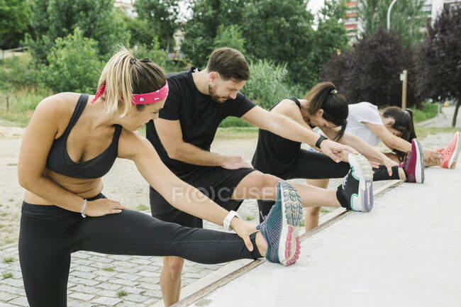 Grupo de pessoas que se estende ao ar livre com seu treinador após o treinamento — Fotografia de Stock