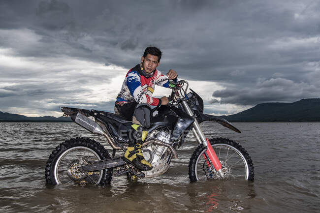 Mann posiert mit seinem Dirt-Bike in einem See in der Nähe von Pak Chong / Thailand — Stockfoto