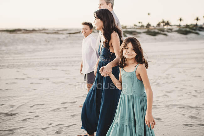 Famiglia felice che cammina insieme sulla spiaggia tenendosi per mano — Foto stock