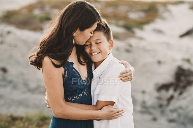 Любящая мать обнимает улыбающегося малолетнего сына — стоковое фото