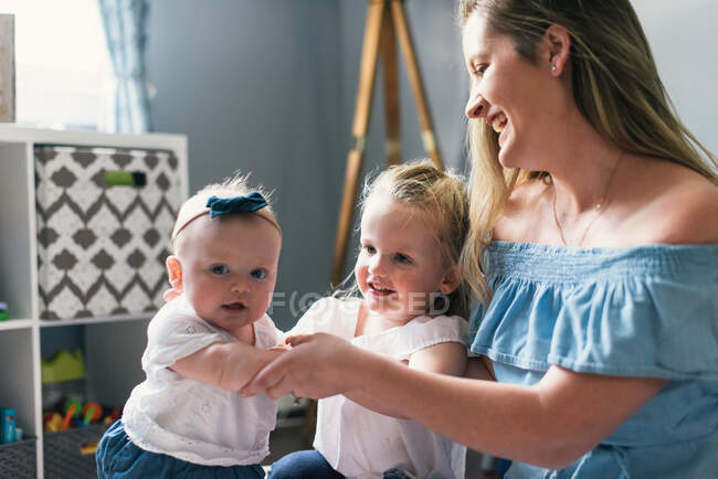 Happy young mother playing together with kids on floor — Stock Photo