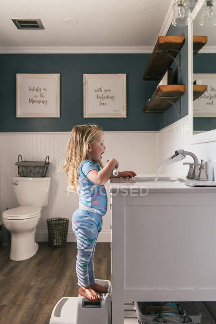 Mignonne petite fille se lave les mains dans la cuisine — Photo de stock