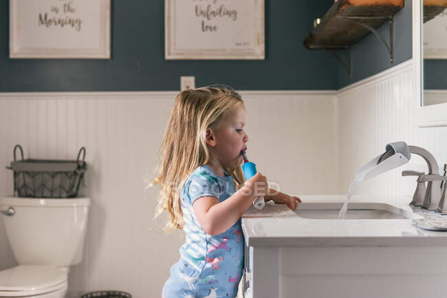 Petite fille lave un évier dans la cuisine — Photo de stock